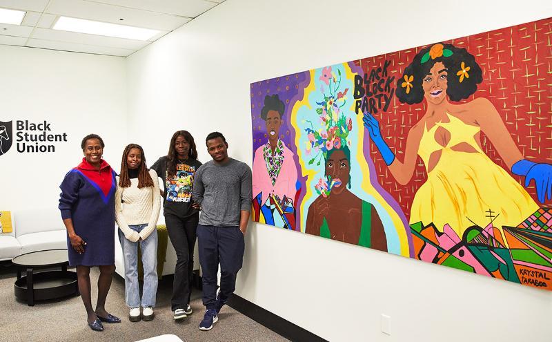 Instructor Susan Romeo-Gilbert with students from the Black Student Union next to the new Black Block Association mural