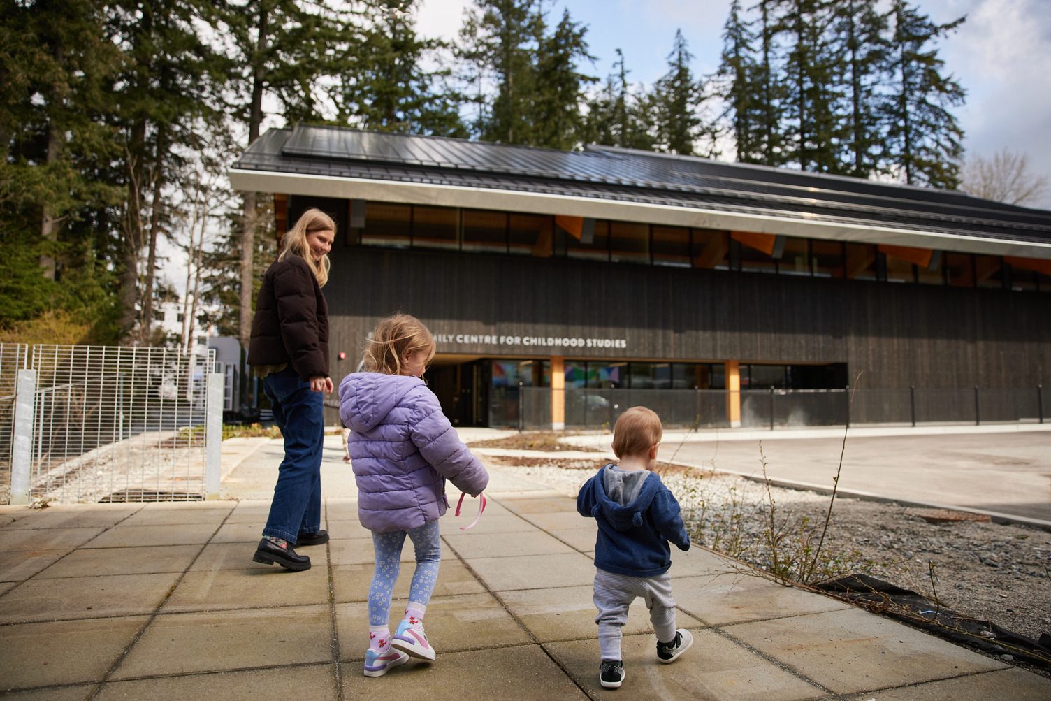 A parent and children walking outside the Fulmer Family Centre for Childhood Studies at Capilano University