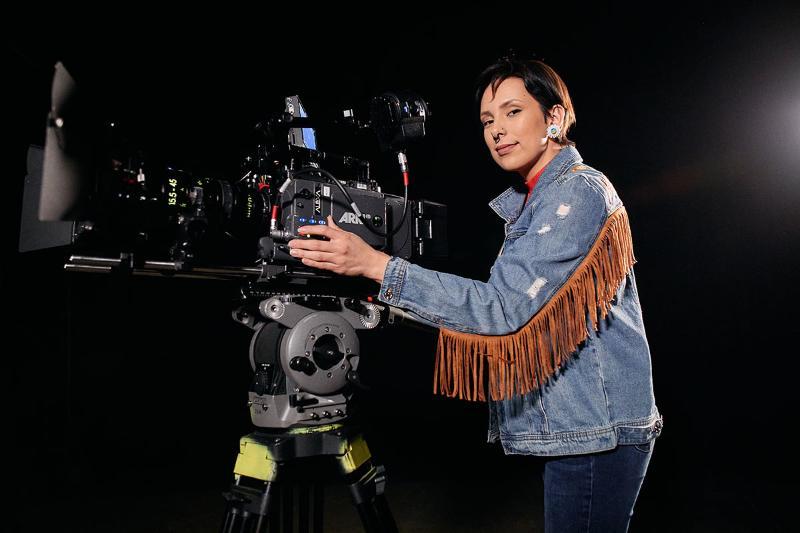 CapU Indigenous Digital Filmmaking student standing behind a camera.
