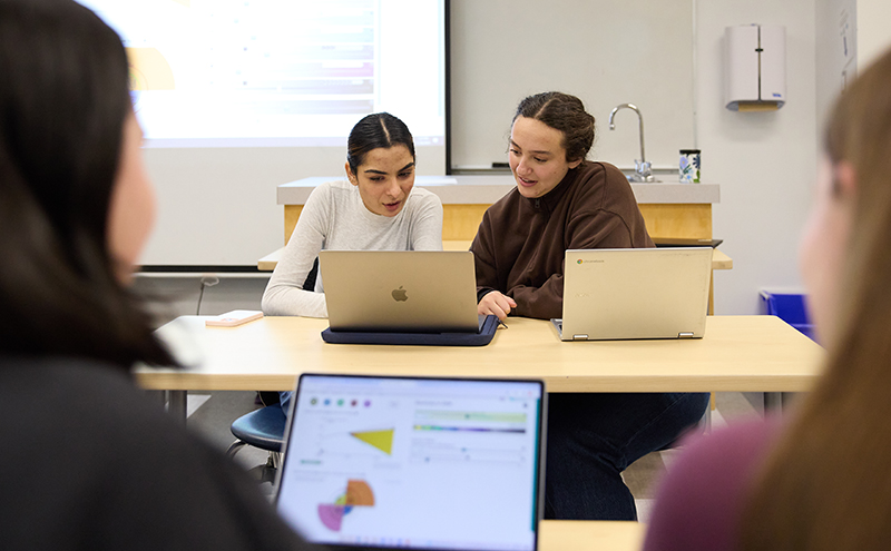 Students in a classroom sharing a laptop