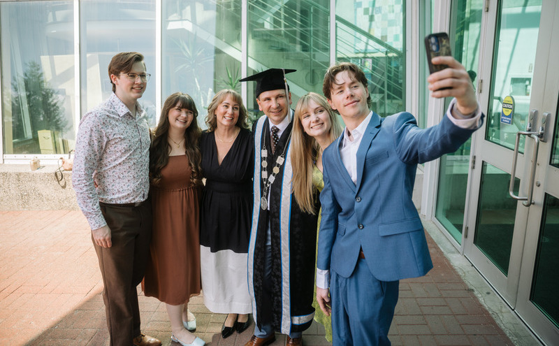 Caption: President Jason Dewling shared a candid moment with family following the ceremony, smiling as they captured a celebratory selfie together.