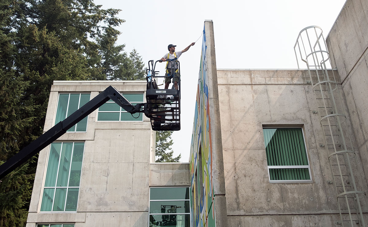 Photo of Andrew Tavukciyan working on his mural