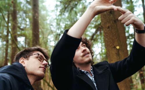 Two students in the woods working on a school project 