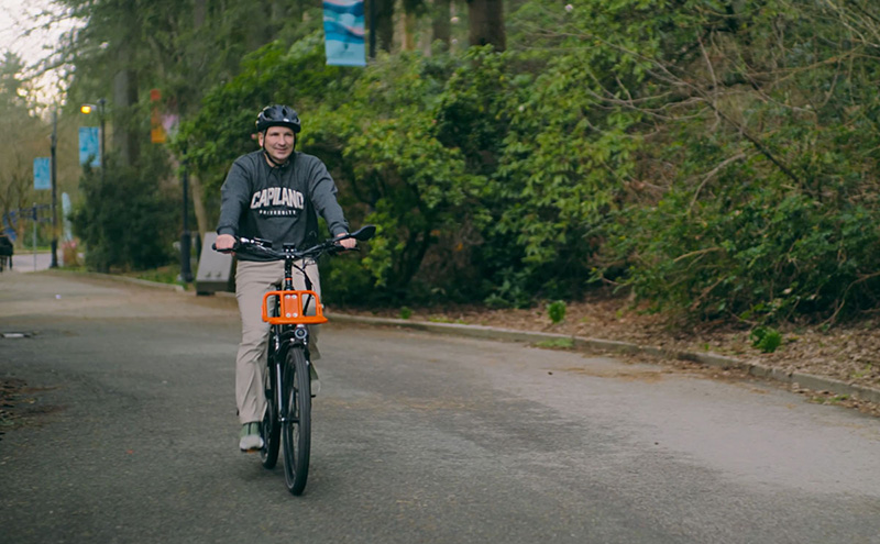CapU president Dr. Jason Dewling riding a bike at North Vancouver campus.