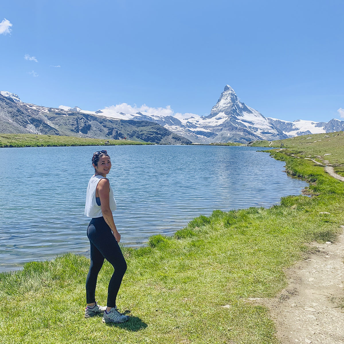 Student standing by body of water with mountain in background