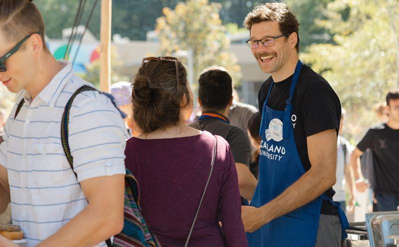CapU’s Associate Vice-President of Student Success Daniel Lavangie chats with guests while handing out burgers to students at the barbecue.