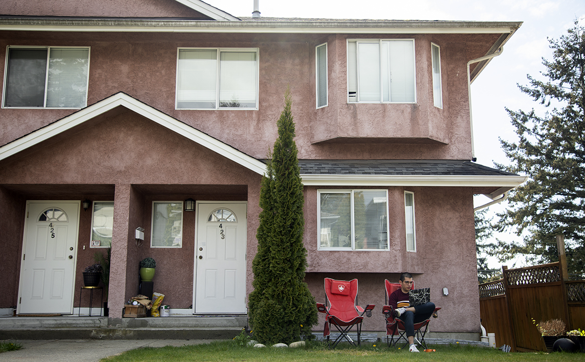 Rodrigo Quezada sitting with laptop, studying outside his house