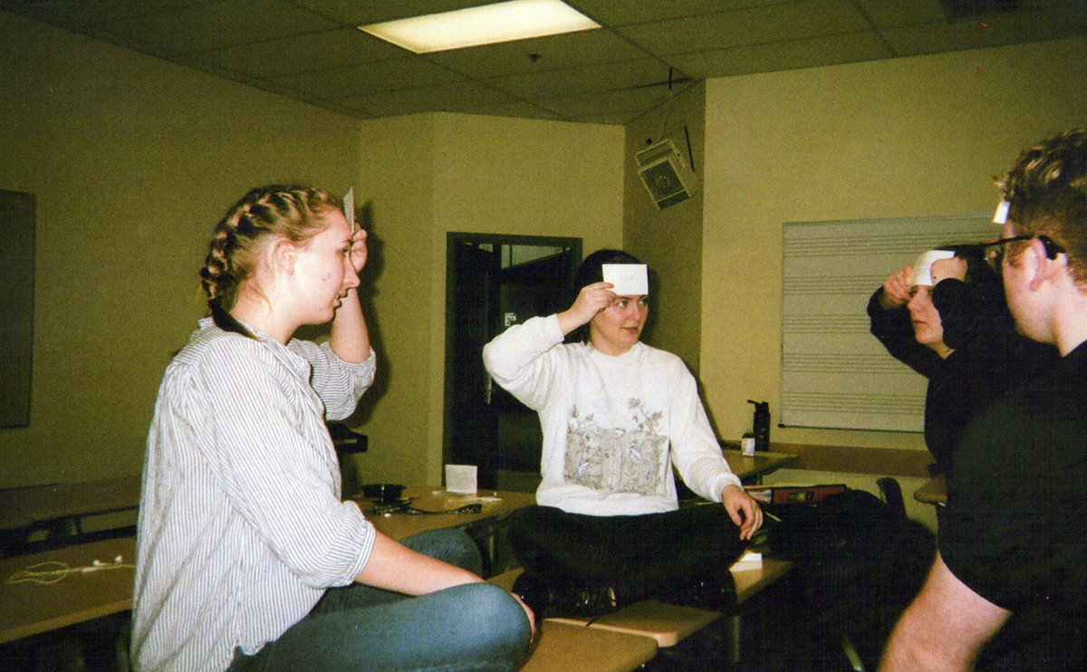 Students holding cue cards on their foreheads