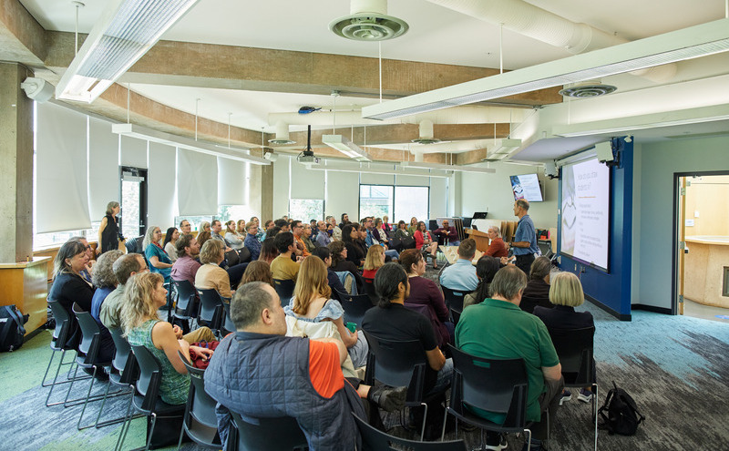 A room full of people listening to a presentation