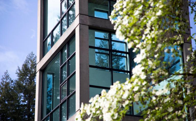 Close-up angled view of the library building at the CapU North Vancouver campus with spring blossoms and evergreen trees.