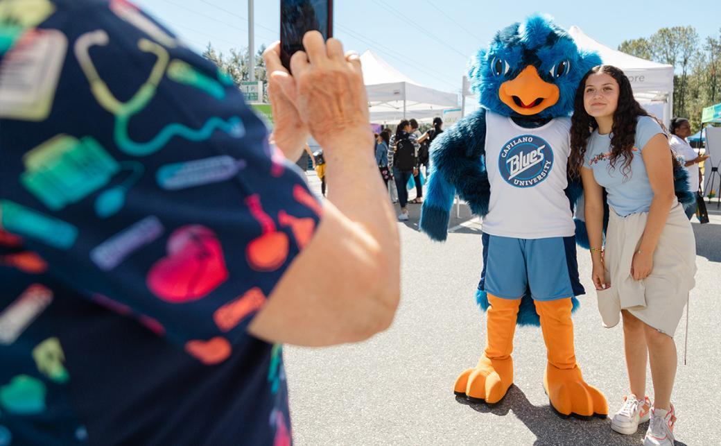 Student taking photo of Jay, the CapU mascot