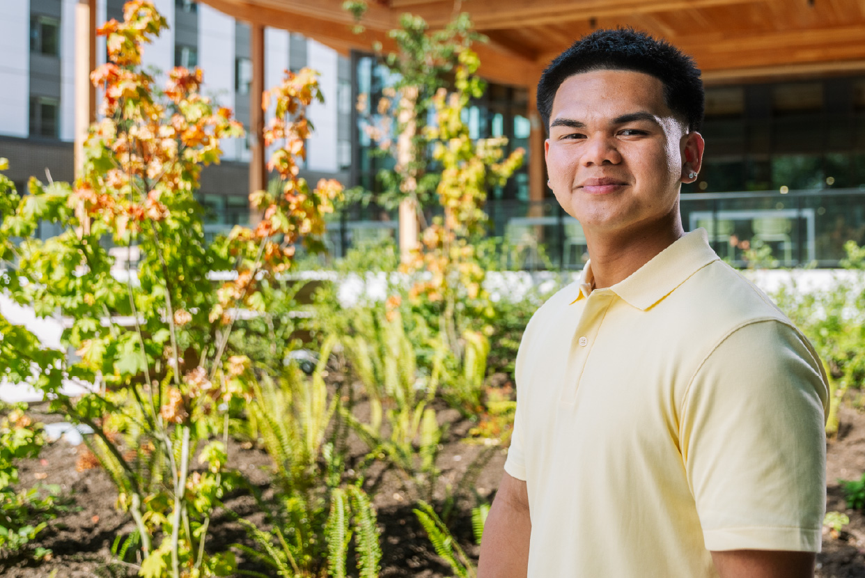 Portrait of a student standing indoors in a green space at CapU.