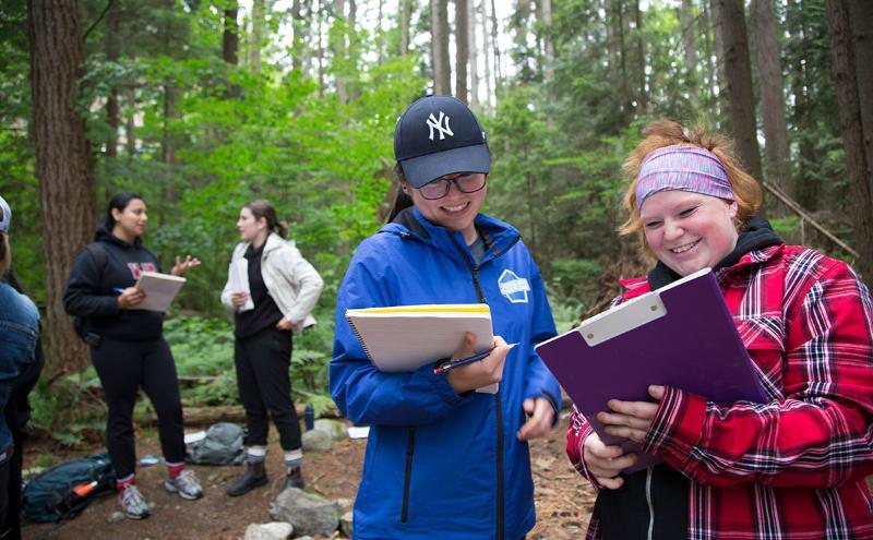 Students in the woods talking about a project