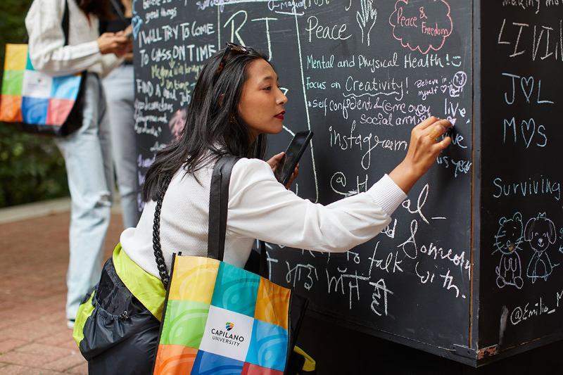 CapU student writing on a public chalkboard at CUSP 2023. 
