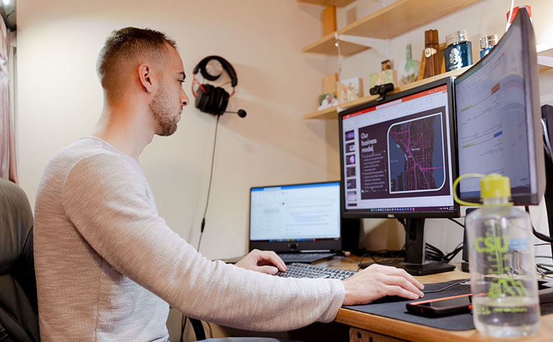CapU student working on three monitors.