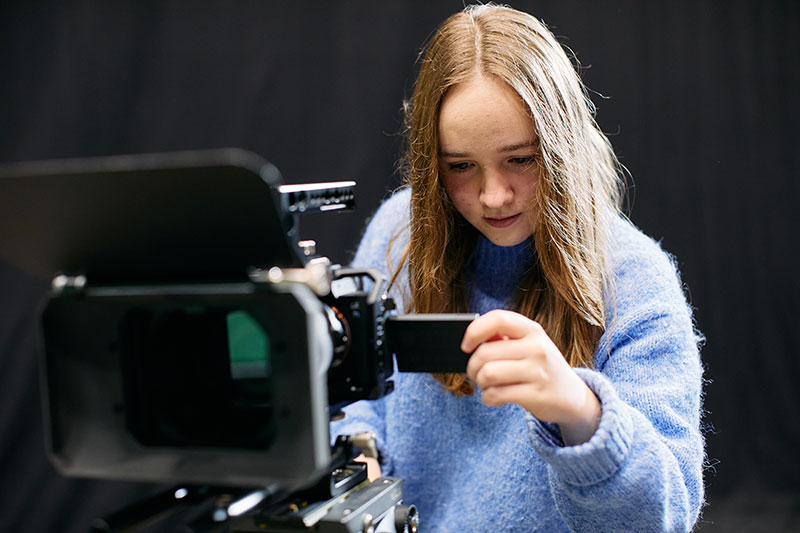 CapU Documentary student setting up a shot with her camera.