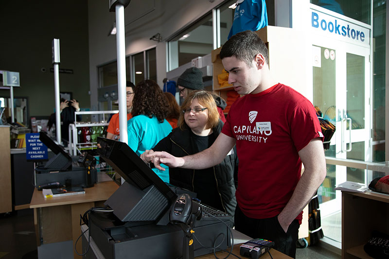 CapU Education & Employment Access Certificate student working at a retail sales till.