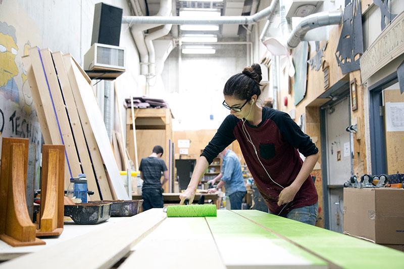 CapU Technical Theatre student painting some boards green. 