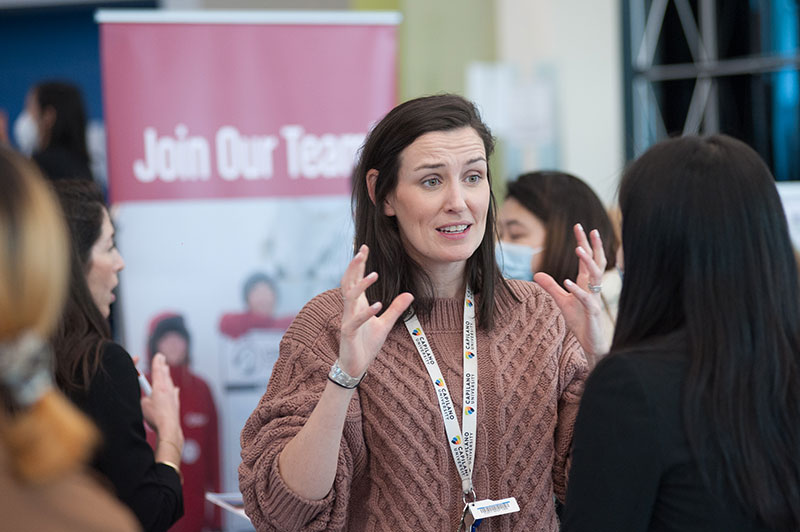 CapU tourism management instructor talking to a student at a hiring fair.