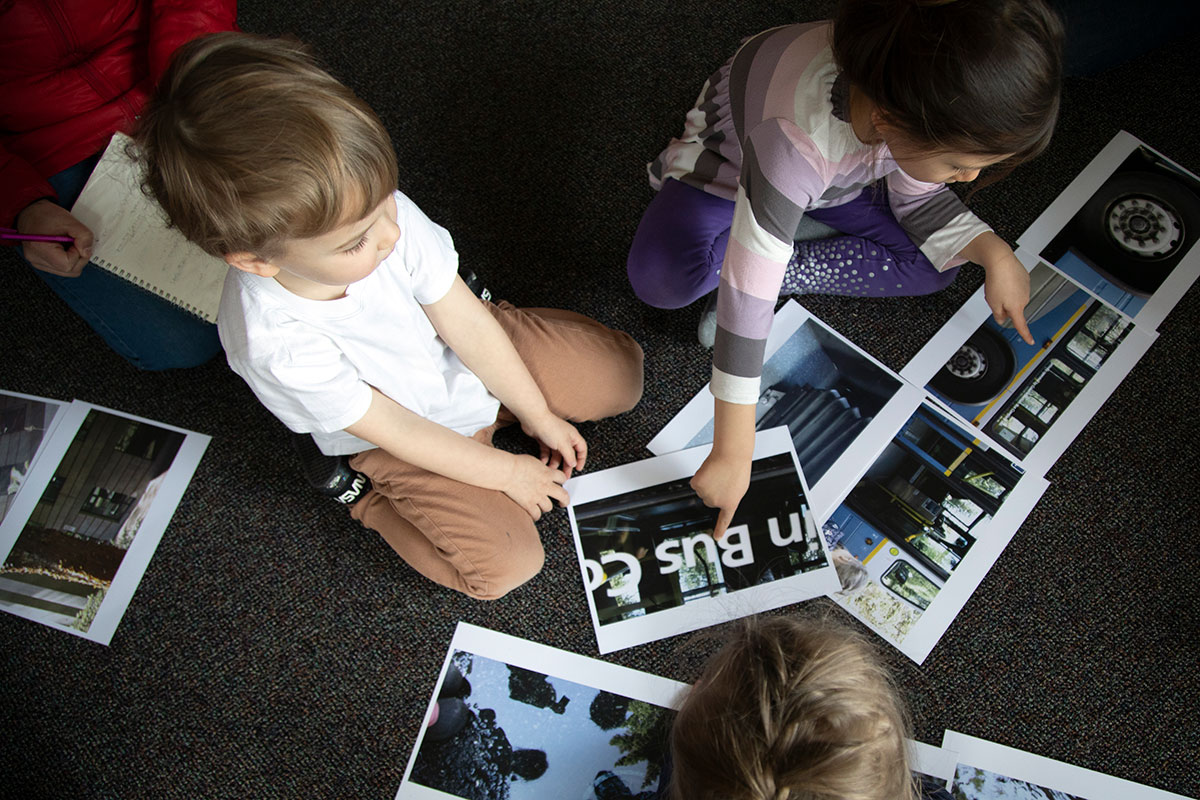 Children on the floor looking at pictures.