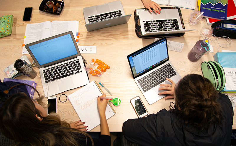 Students at table working on laptops