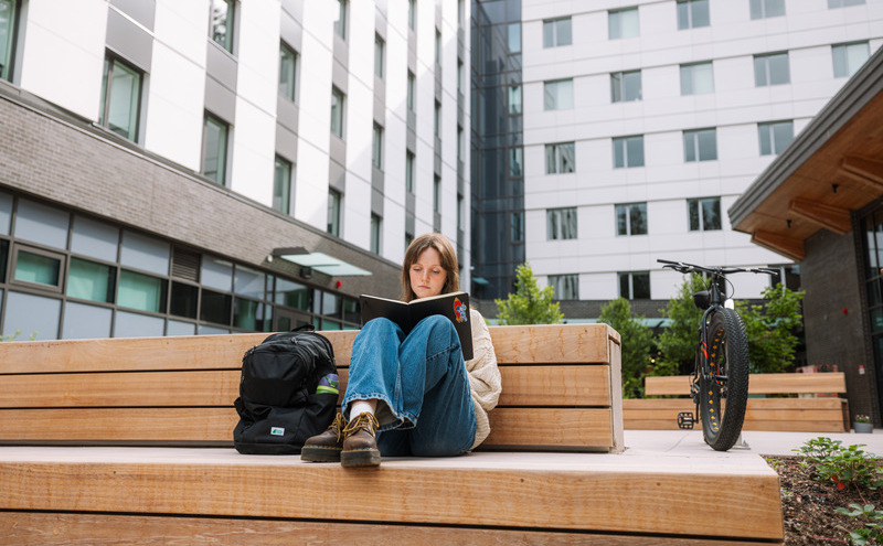 A student sat outside the Treehouse on their laptop